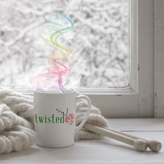 twisted mug in front of a window with thick yarn and needles